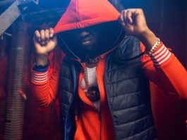 Rapper in red hoodie poses in grunge studio