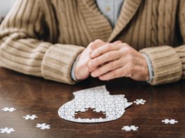 cropped view of senior man playing with puzzles on table