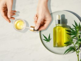 Pipette with CBD cosmetic oil in female hands with bottle of cannabis oil and hemp leaves, marijuana