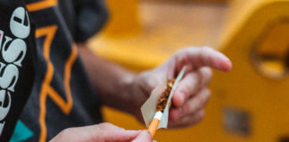 Anonymous guy rolling up joint on street