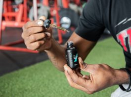 Male holding Resilience CBD Oil dropper at the gym.