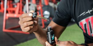 Male holding Resilience CBD Oil dropper at the gym.