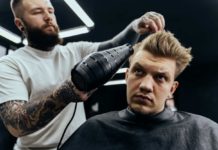 Barber drying male hair in hairdressing salon