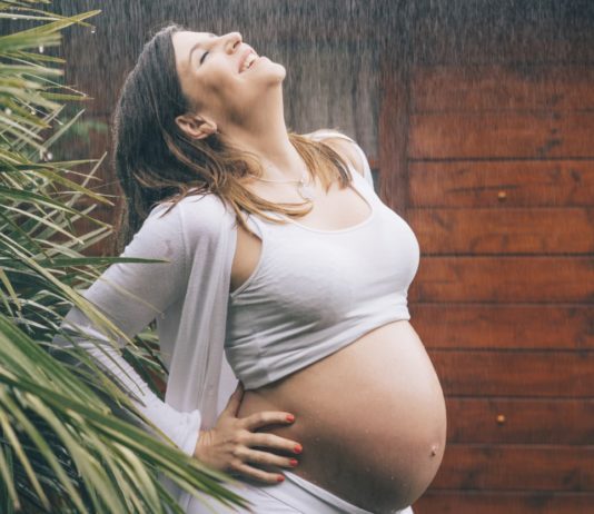 Beautiful pregnant woman posing in the rain.