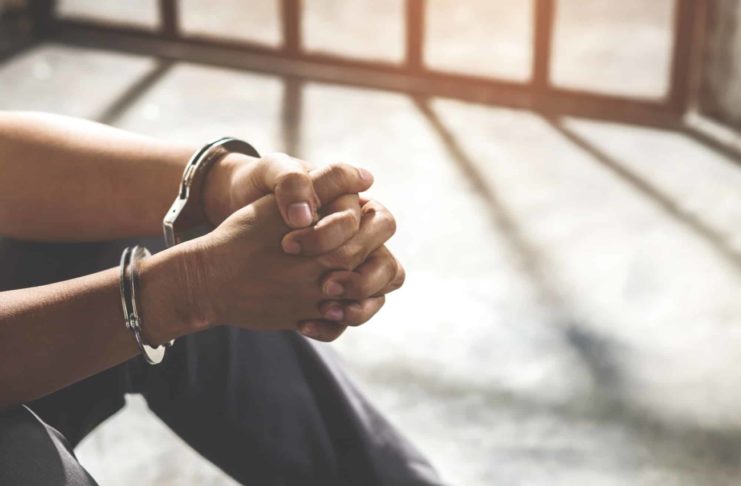 The prisoner is sitting in his cell and desperate, holding his head in his hands.