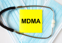 Yellow sticker with text MDMA lying on the masks and stethoscope. Medical concept