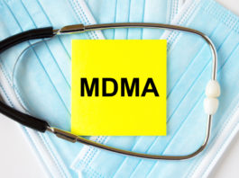 Yellow sticker with text MDMA lying on the masks and stethoscope. Medical concept
