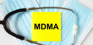Yellow sticker with text MDMA lying on the masks and stethoscope. Medical concept