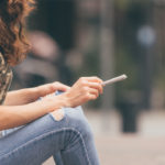 Young female holding a marijuana joint in her hand, ready to smoke. Urban weed smoking.