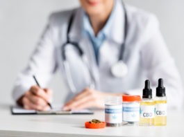 selective focus of dried marijuana, bottles with cbd and medical cannabis lettering near doctor writing prescription