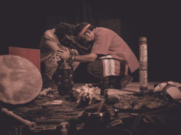 shaman or sorcerer men giving sangha medicine, ayahuasca, during prehispanic ritual on black background