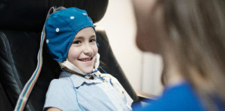 Portrait of Smiling Autistic Girl Undergoing an EEG Examination
