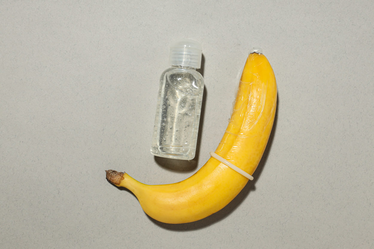 A condom on a banana with a bottle of lubricant