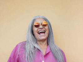 Senior woman wearing hippie sunglasses while laughing on camera - Gray hair granny smiling