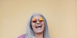 Senior woman wearing hippie sunglasses while laughing on camera - Gray hair granny smiling