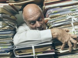 Panicked businessman overloaded with paperwork