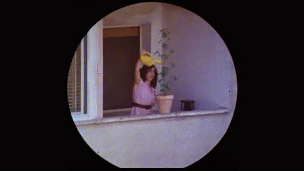 Carmen Maura riega con esmero su planta mientras es vigilada por un policía que no sospecha de la trampa, en “Pepi, Luci, Bom y otras chicas del montón” (1980)
