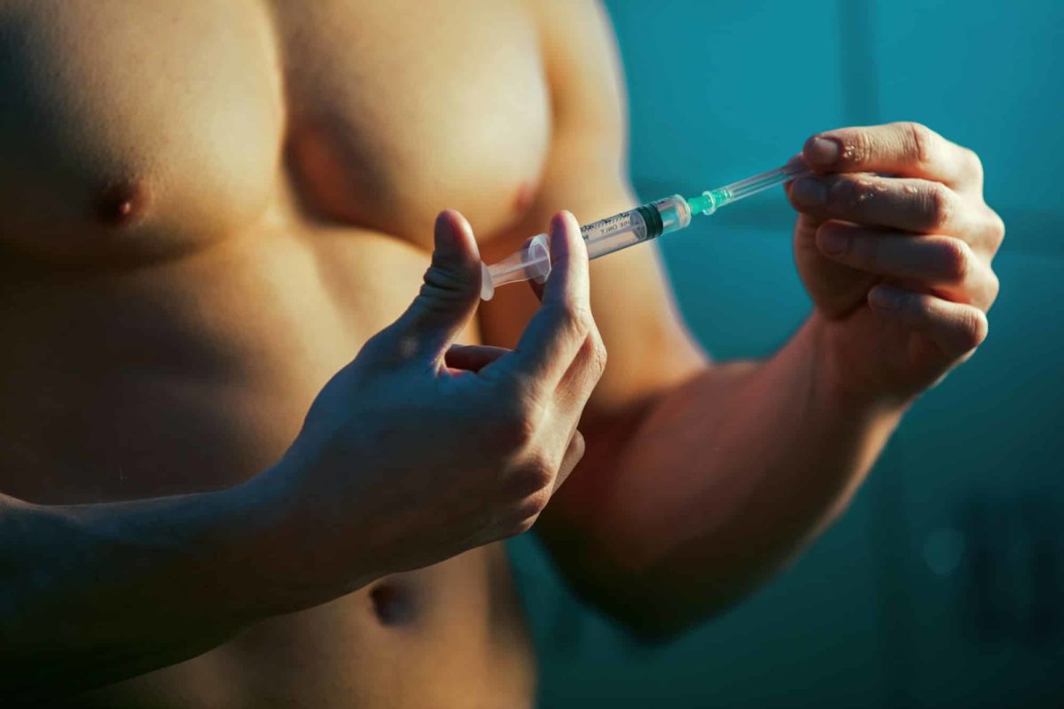 Close up of muscular athlete with injection of performance-enhancing drugs.