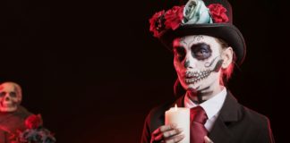 Woman lighting candle for magic ritual in graveyard, celebrating Day of the Dea