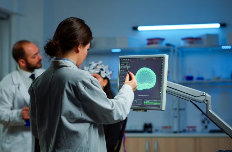 Researcher looking at monitor analysing brain scan