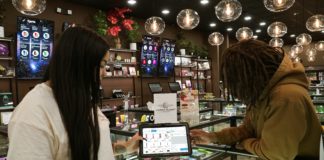 Budtender is sharing a POS tablet with product information with consumers. Hip to hip interaction.