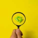 Crop person holding magnifier above pills
