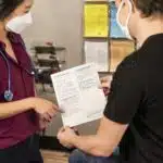 In this 2020 photograph, captured inside a clinical setting, a health care provider and patient, consult on influenza vaccine options. The best way to prevent seasonal flu illness, is to get vaccinated every year. Centers for Disease Control and Prevention (CDC) recommends everyone 6-months of age and older get a flu vaccine every season. There are many vaccine options to choose from, but the most important thing, is for all people 6-months and older, get an influenza vaccine every year.