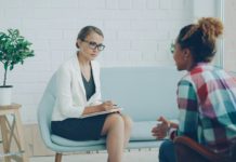 UNM prueba psilocibina en terapia grupal para TEPT Confident female psychologist is holding professional consultation with African American girl, listening to her and writing while patient is speaking explaining problem.