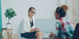 UNM prueba psilocibina en terapia grupal para TEPT Confident female psychologist is holding professional consultation with African American girl, listening to her and writing while patient is speaking explaining problem.