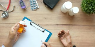 Hand holding medicine over paper on desk