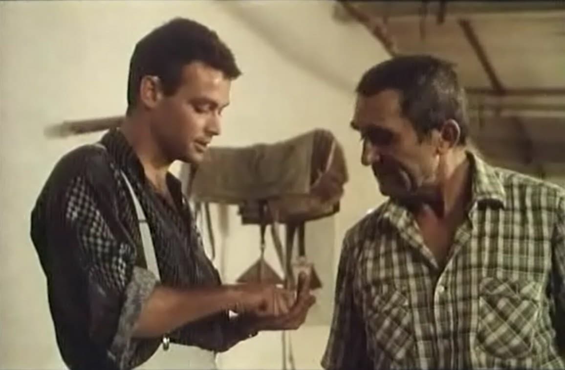 Dos hombres con camisas de cuadros observan un pequeño objeto sostenido por uno de ellos.