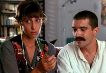 El cannabis en el cine español de los años 80 Una mujer sostiene un cigarrillo liado mientras un hombre con bigote observa su mano.