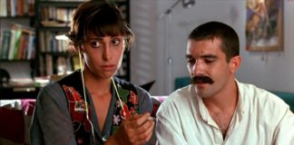 Una mujer sostiene un cigarrillo liado mientras un hombre con bigote observa su mano.