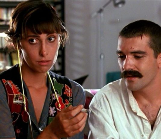 El cannabis en el cine español de los años 80 Una mujer sostiene un cigarrillo liado mientras un hombre con bigote observa su mano.