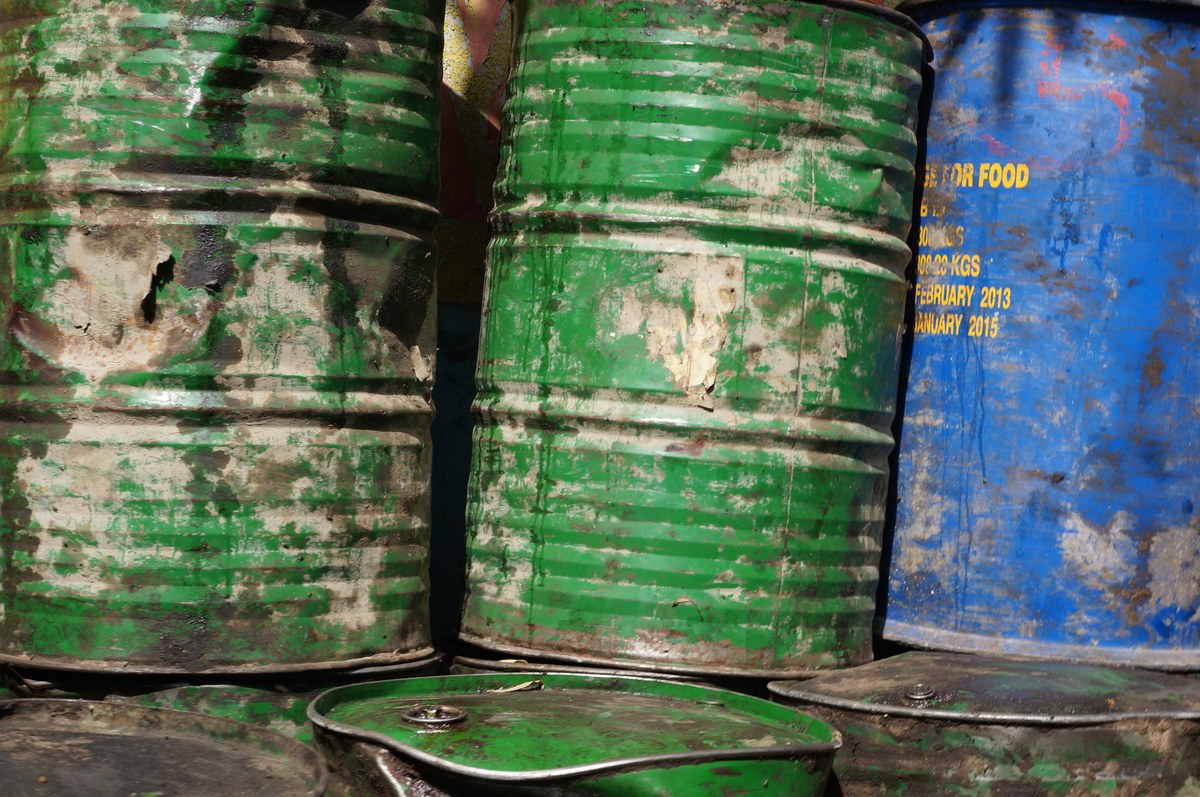 Bidones industriales verdes y azules, apilados y con la superficie desgastada