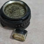 Cazoleta circular con malla metálica y pequeño recipiente de vidrio con restos de extracto