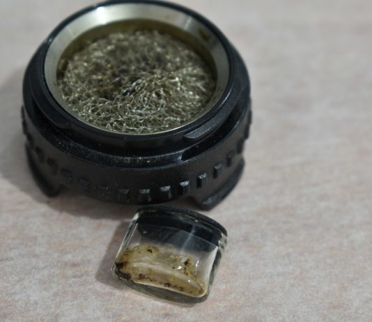 Cazoleta circular con malla metálica y pequeño recipiente de vidrio con restos de extracto