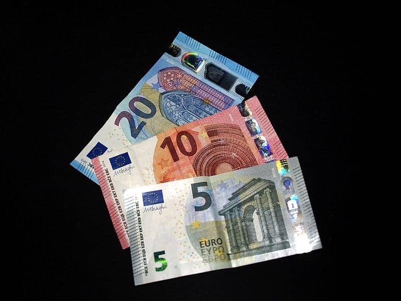 Billetes de 5, 10 y 20 euros superpuestos sobre un fondo negro