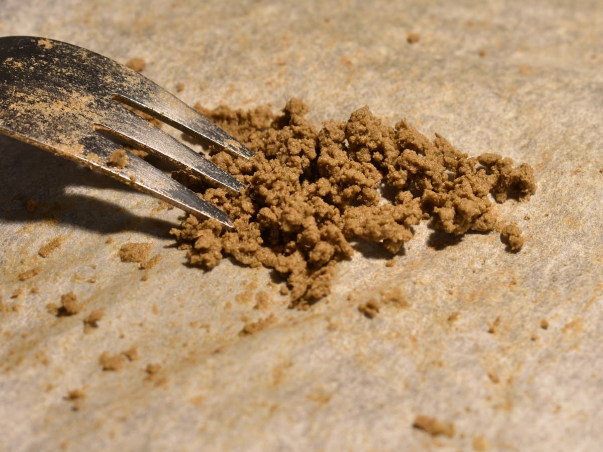 Primer plano de un tenedor separando pequeños grumos marrones de la extracción