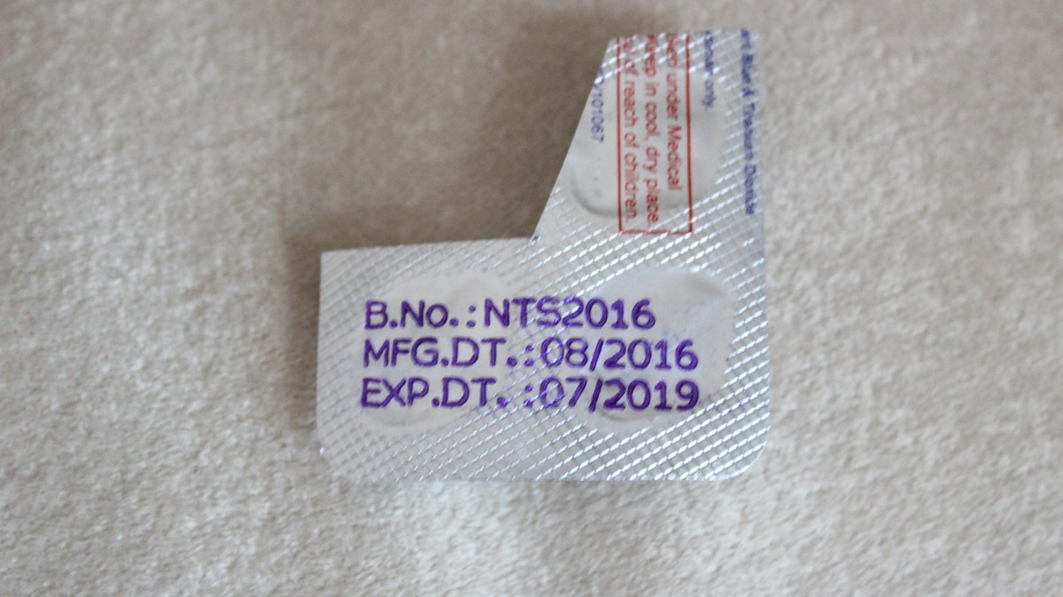 Fragmento de blíster plateado con números de lote y fechas de fabricación y caducidad impresos