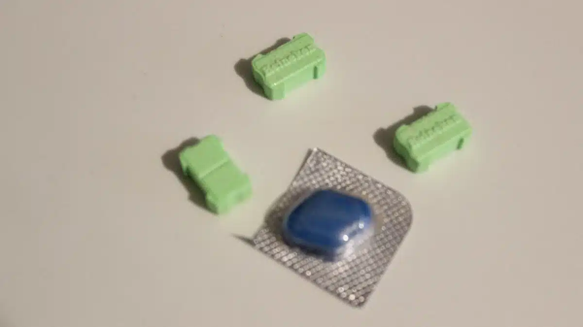 Comprimido azul en un blíster junto a tres pastillas verdes rectangulares