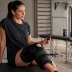 Persona en rehabilitación por una fractura de meseta tibial con la rodilla apoyada y un frasco de aceite de CBD sin marca
