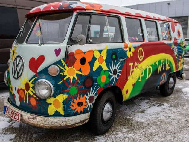 Furgoneta cl&aacute;sica decorada con flores, corazones, s&iacute;mbolos de paz y colores vivos