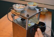 Rosin de hachís y líquido: variables y proceso Prensa de extracción con papel plegado que dirige un líquido oscuro hacia un frasco sostenido a mano.