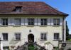 El cannabis en Heliópolis de Ernst Jünger Fachada de una casa histórica con tejado de tejas, ventanas enrejadas y escalinata adornada con flores.