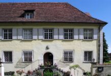 El cannabis en Heliópolis de Ernst Jünger Fachada de una casa histórica con tejado de tejas, ventanas enrejadas y escalinata adornada con flores.