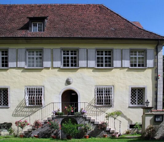 El cannabis en Heliópolis de Ernst Jünger Fachada de una casa histórica con tejado de tejas, ventanas enrejadas y escalinata adornada con flores.