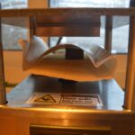 Papel de horno plegado entre las placas de una prensa t&eacute;rmica met&aacute;lica.