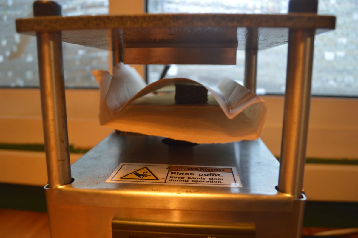 Papel de horno plegado entre las placas de una prensa térmica metálica.