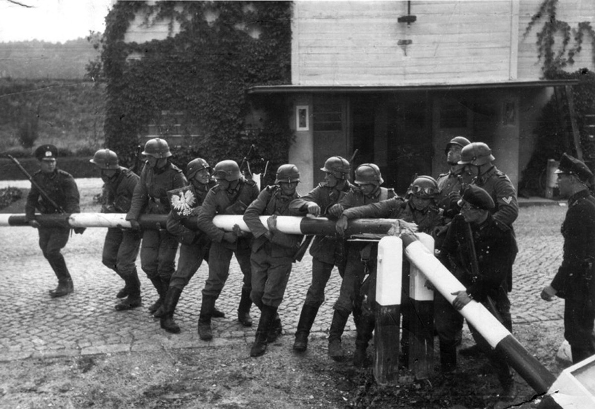 Grupo de soldados uniformados retira una barrera de madera en una escena hist&oacute;rica en blanco y negro.
